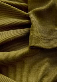 Olivengrønt ribbet stof med en blød tekstur, der har lette variationer i farvetone og fine, lodrette striber, som giver et lagdelt udseende.