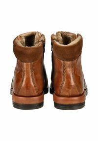 Braune Leder-Stiefeletten mit einem weichen, hellbraunen Wildlederschäfte, mit Futter aus Fell, seitlichen Reißverschlüssen und Gummisohlen. Fein gestickte Details sind sichtbar.