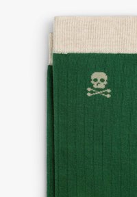 Medias de punto verdes con un puño en crema, que presentan un pequeño diseño de calavera y tibias en beige. Tejido texturizado con un ajuste ceñido.