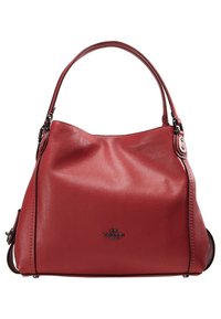 Sac hobo en cuir rouge à texture douce, forme incurvée, bandoulière unique et petit logo sur le devant.