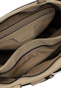 Interno di una borsa in pelle color tan con più scomparti, inclusa una tasca con cerniera. Presenta un tessuto liscio e cuciture a contrasto.
