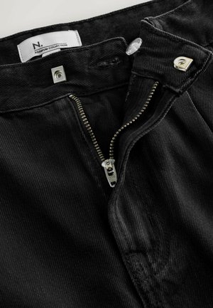 Schwarze Cordhosen mit Reißverschluss aus YKK, Druckknopfverschluss und Premium-Kollektion-Label, das einen strukturierten Stoff betont.