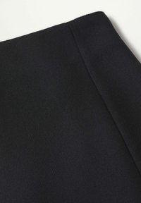 Tissu noir à surface texturée, présentant un bord plié. Le matériau semble lisse, sans motifs ni ornements.