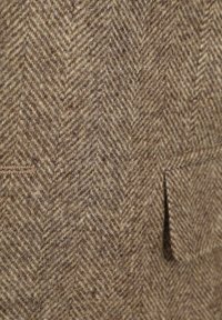 Bruin herringbone-patroon stof met een grove textuur; twee zichtbare zakken en nette stikdetails. Zachte wolachtige uitstraling.