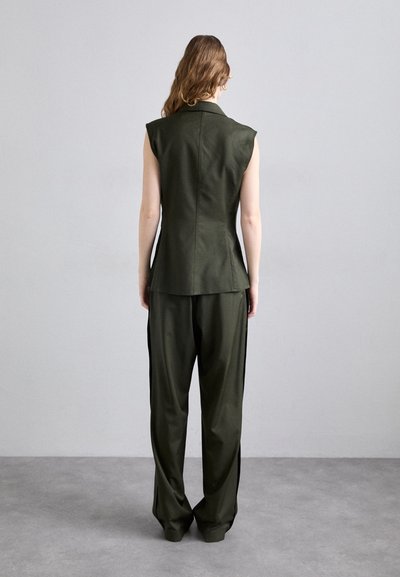 Blazer sem mangas verde escuro combinado com calças de perna larga, apresentando um design estruturado e uma textura suave.