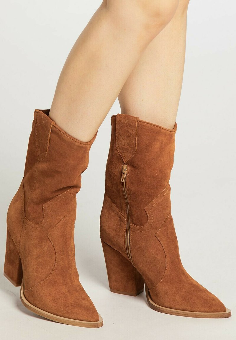 Ruske suede cowboy saapaat, joissa on terävä kärki, keskipitkä varsi, koristeellinen ommel ja sivuvetoketju; paksu korko lisää vakautta.