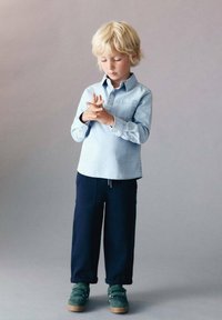 Světle modrá džínová košile, námořnické široké kalhoty a zelená obuv. Obsahuje límeček na knoflíky a ohrnuté rukávy. Jednoduchý, uvolněný design.