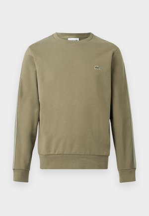 Olive green long-sleeve crewneck sweatshirt with ribbed cuffs and hem, featuring a small crocodile logo on the left chest and stripe detail on sleeves.
