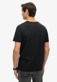 Zwarte katoenen T-shirt met korte mouwen, ronde halslijn en een relaxte pasvorm. Gladde textuur zonder zichtbare patronen of accenten.