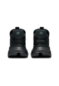 Zwarte sportschoenen met een gestructureerde bovenkant, strapontwerp en gevoerde hakken, met een verhoogd logo en "SWISS ENGINEERING" detail.