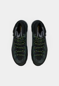 Botas de caminhada pretas com um upper texturizado, atacadores verdes e amarelos, biqueira reforçada e uma sola de borracha robusta, projetadas para durabilidade e suporte.