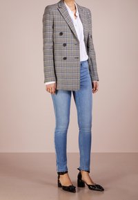 Dubbelknäppt grått rutigt blazer med svarta knappar, matchat med ljusblå skinny jeans och svarta lackläderklackar. Vit skjorta under.