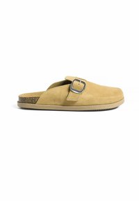 Bežiniai suede slip-on batai su plačia dirželiu, keturkampiu metaliniu užsegimu ir kamštiniu padu. Lygus guminis padas su tekstūruota paviršiumi geresniam sukibimui.