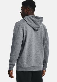 Grå hoodie med en blød tekstur, der har en snøre i hætten, lange ærmer og en afslappet pasform. Kantene og manchetterne er ribbede.