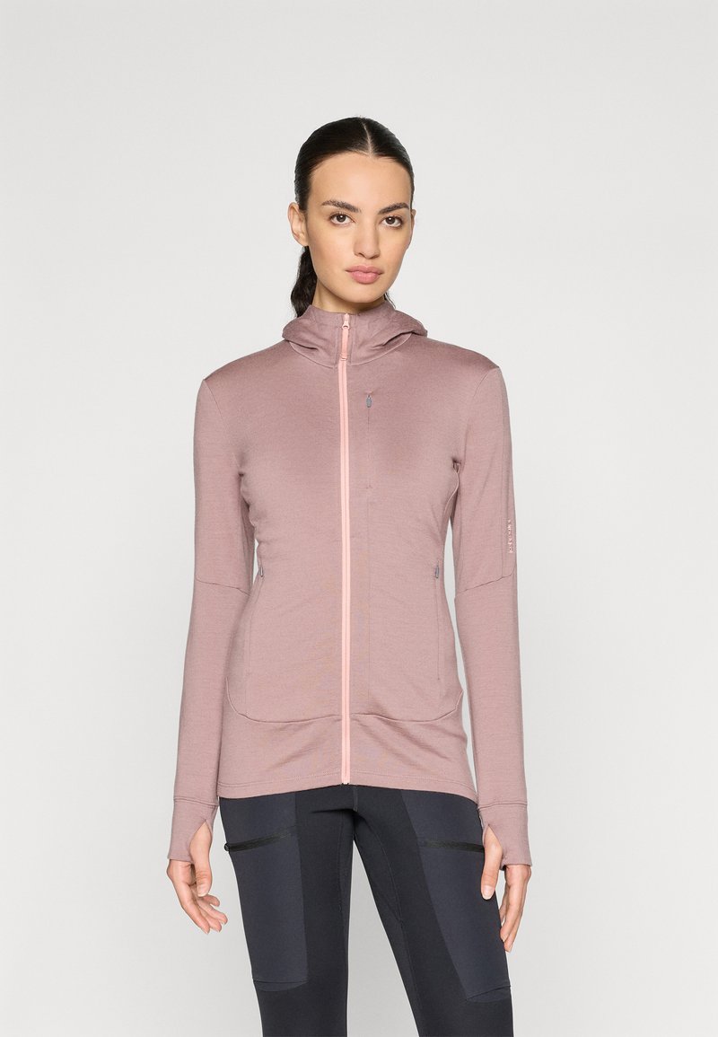 Casaco desportivo rosa com fecho éclair, capuz, mangas longas e buracos para os polegares. Apresenta detalhes contrastantes no fecho e nos bolsos. Textura suave.