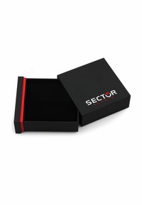 Scatola di cartone nero con chiusura magnetica, caratterizzata da una banda di accento rossa e il logo bianco "SECTOR NO LIMITS" sulla parte superiore. L'interno è nero.