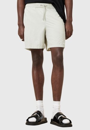 Lysegrønne shorts med elastisk liv og snøre detaljer. Bærers med sorte sandaler og hvite sokker. Enkelt design, ingen mønstre.