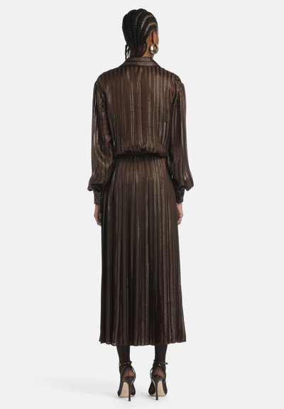 Vestido marrón plisado con rayas verticales brillantes, mangas largas y cintura ajustada, combinado con zapatos de tacón alto. Textura suave.