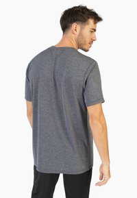 Grijze t-shirt met korte mouwen van een gestructureerd, geribbeld materiaal; heeft een rechte snit en een detail bij de achterkant van de halsnaad.