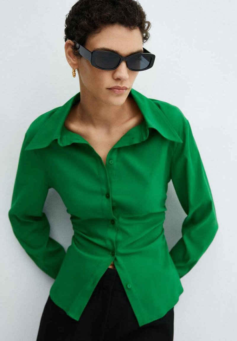 Groene, langarmige button-up shirt met een puntige kraag en een getailleerd ontwerp. Draagt het met een donkere broek en accessoires met een zwart zonnebril.