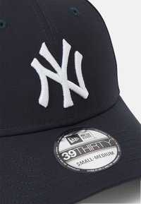 Navy cap with an embroidered white NY logo, featuring a curved brim, textured fabric, and a New Era size sticker labeled 39THIRTY, small-medium.