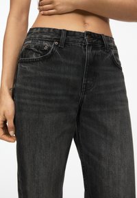 Zwarte denim jeans met hoge taille, vijf-pocket ontwerp, subtiele vervaging, gestikte details en knoopsluiting met klinknagels.
