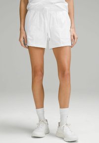 Pantalones cortos deportivos blancos con una cinta elástica en la cintura, detalle de cordón y bolsillos laterales. Tejido suave con un corte relajado y dobladillo.