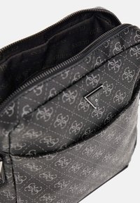 Borsa nera sintetica con motivi in rilievo; presenta una chiusura con zip e un'accents triangolare con logo; interno foderato in tessuto brandizzato.