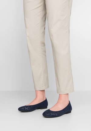 Granatowe baleriny zamszowe z laserowo wycinanymi wzorami kwiatowymi i zaokrąglonym noskiem, zestawione z jasnobeżowymi spodniami 7/8.