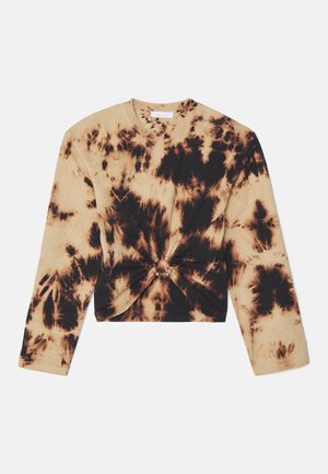 Cropped tie-dye long-sleeve shirt in beige and black, featuring a twisted front detail with decorative hardware. Soft cotton material.