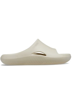 Beige Slip-On Crocs Sandale mit geschlossenem Zehenbereich, seitlichen Belüftungslöchern, strukturierter Sohle und geprägt eingestanztem Markennamen auf der Oberseite.