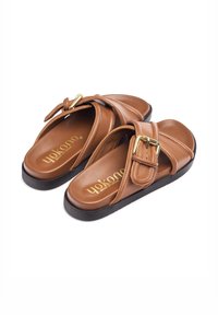 Sandali slide in pelle marrone con una larga fascia, hardware in oro e suola in gomma nera. Suoletta testurizzata e logo del marchio visibile.