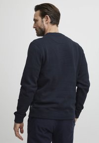 Námořnický crewneck svetr z měkké bavlny, s žebrovanými manžetami a lemem, hladkým povrchem a minimálními švy.