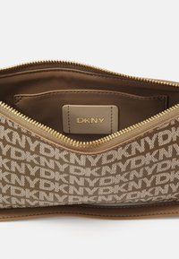 DKNY branded purse with a zip closure. Features a brown textile exterior with a repeated logo pattern, and a smooth inner lining.