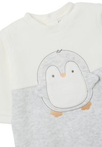 Helles graues und weißes Babykleidungsstück aus weichem Stoff, das in der Mitte ein Pinguinmotiv mit gestickten Details und einem Druckknopfverschluss am Kragen aufweist.