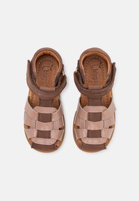 Brązowe i beżowe sandały z połączeniem błyszczących i matowych tekstur, podwójnymi paskami na rzepy oraz otwartym noskiem.