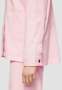 Roze denim jack met een ontspannen pasvorm, zijslitsen en knoopmanchetten. Gladde tekstuur met zichtbare stikdetails.