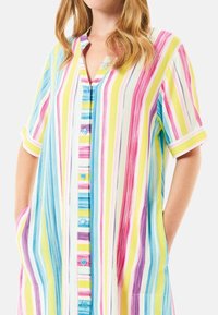Vestido de camisa a rayas con rayas verticales en azul, amarillo, rosa y púrpura. Mangas cortas, cierre de botones en la parte delantera y bolsillos laterales. Tejido suave.