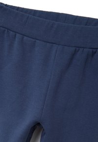Gros plan sur un pantalon doux en tissu bleu marine avec une taille élastique et des coutures visibles à l'avant.