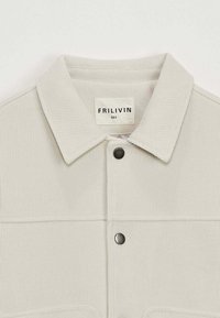 Veste en velours côtelé gris clair avec un col classique, fermeture à boutons-pression à l'avant et étiquette indiquant la taille et la marque. Fini en tissu texturé.