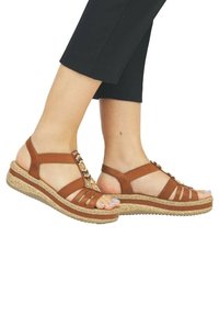 Bruine leren sandalen met een geweven riemontwerp, kurken zool en kralenaccenten. Voorzien van een comfortabele sleehak en open-toe stijl.