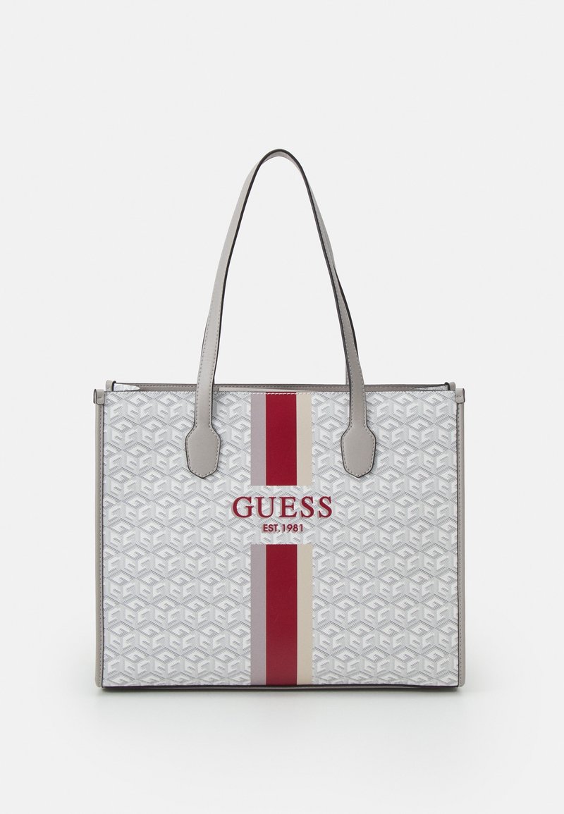 Sac fourre-tout en blanc et gris avec un motif géométrique, des accents rayés rouges et crème, des poignées en cuir, et un logo avec l'année de création.