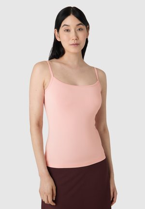Top in cotone leggero rosa clair con spalline sottili, scollatura rotonda e una texture di tessuto liscia. Indossato con una gonna marrone scura.