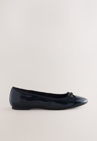 Chaussure de ballet plate en cuir verni noir avec bout arrondi et petit nœud décoratif sur le dessus, vue de profil.