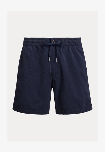 Un short de bain bleu marine présente un tissu texturé, une taille élastique avec cordon de serrage, et des poches latérales pour le rangement.