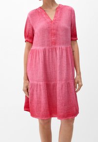 Robe rose à manches courtes en tissu texturé, avec un décolleté en V, des détails de boutons et des volants froncés pour un ajustement décontracté.