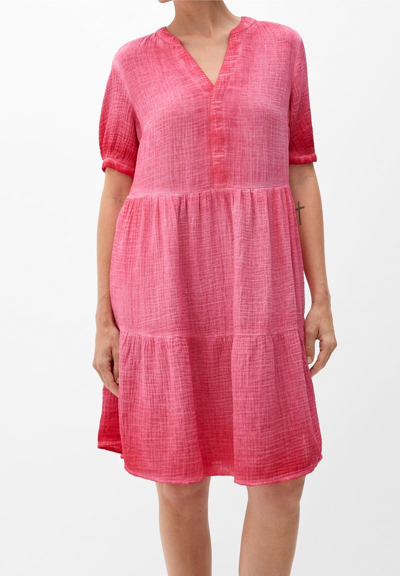 Robe rose à manches courtes en tissu texturé, avec un décolleté en V, des détails de boutons et des volants froncés pour un ajustement décontracté.
