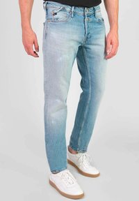 Lichtblauwe denim jeans met een slim fit, vervaagde plekken, vijf zakken en een subtiele stikselafwerking, gecombineerd met witte sneakers.
