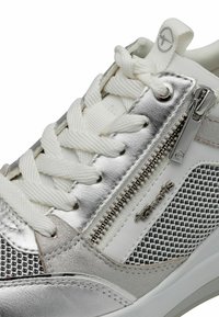 Weiße Sneaker mit silbernen Akzenten, ausgestattet mit einem Obermaterial aus Mesh, dicken weißen Schnürsenkeln und einem seitlichen Reißverschluss für einfaches An- und Ausziehen. Markenname sichtbar.
