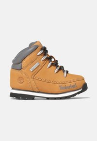 Brun läderstövel med grå akcenter, metalöglor, svarta snören och en vitrandig gummisula. Har Timberland-logotyp.